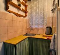 Küche in einer Hütte mit Holzdekor, Regal und Vorhang am Fenster.