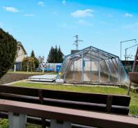 Ein Garten in Partizánske mit einem Folientunnel, Gras und einem kleinen Beet.