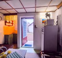 Das Innere der Hütte mit Küche, Sofa und offenen Türen zum Garten.