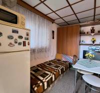 Eine kleine Küche in der Hütte mit Holzelementen, einem Esstisch und einem Kühlschrank.