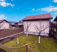 Ein Garten mit einer Hütte in Partizánske, Obstbäume und bewirtschaftetes Land, klarer Himmel.