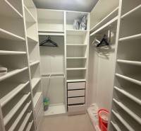 Ein Kleiderschrank in einer 3-Zimmer-Wohnung mit weißen Regalen und Wandhaken.