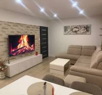 Wohnzimmer in einer 3-Zimmer-Wohnung mit Ecksofa und Boden in Holzoptik.