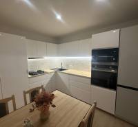 Moderne Küche in einer 3-Zimmer-Wohnung mit weißen Schränken und Marmorverkleidung.