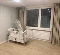 Ein Kinderbett in einer 3-Zimmer-Wohnung mit Holzboden und grauen Vorhängen.