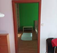 Ein Zimmer mit Bett, grüne Wand, Holzboden, Möbel in einer Einzimmerwohnung.