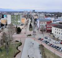 Blick auf die Büros am Freiheitsplatz in Michalovce mit geparkten Autos und Fußgängern.