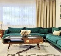 Ein Einfamilienhaus mit einem Sofa in Grüntönen, Holzmöbeln und Kunst an der Wand.