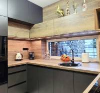 Küche in einem Einfamilienhaus mit dunklen Schränken und einem Boden in Holzoptik.