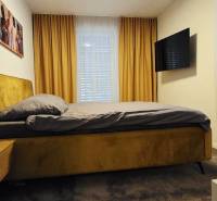 Schlafzimmer in einem Einfamilienhaus mit Bett, Nachttisch, Fernseher und Vorhängen.