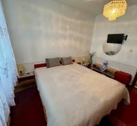 Schlafzimmer in einer 3-Zimmer-Wohnung mit Bett, Kronleuchter und Fernseher an der Wand.