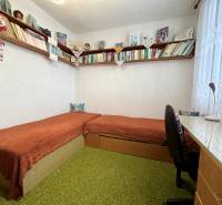 Ein Zimmer in einer 3-Zimmer-Wohnung mit Regalen voller Bücher und einem einfachen Schreibtisch.