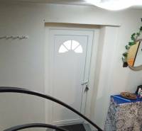 Eingang zum Einfamilienhaus mit weißen Türen, Spiegel und dekorativen Elementen.