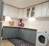 Küche in einem Einfamilienhaus mit weißen und grauen Schränken, Boden mit Holzdekor.