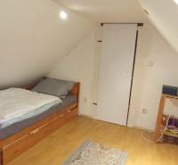 Dachzimmer mit Dachschräge, Bett und Boden in Holzoptik in einem Einfamilienhaus.