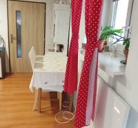 Esszimmer in einem Einfamilienhaus mit rotem Vorhang, Tisch und Boden in Holzoptik.