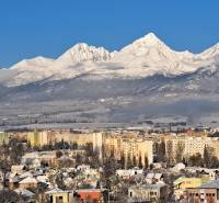 Verschneite Berge mit Blick auf einen Teil der Stadt Poprad und mehrstöckige Gebäude.