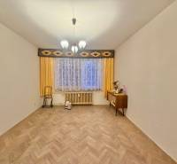 Ein Zimmer in einer 3-Zimmer-Wohnung mit einem Boden in Holzoptik, Vorhängen und einer Kommode.