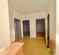 Der Flur in der 3-Zimmer-Wohnung mit hellen Wänden und drei Türen, Boden mit Holzdekor.