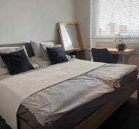 Schlafzimmer in einer 2-Zimmer-Wohnung mit Bett, Schreibtisch und Boden in Holzoptik.