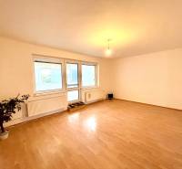 Ein Zimmer in einem Einfamilienhaus mit einem Boden in Holzoptik und großen Fenstern.