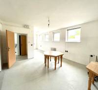 Interieur eines Einfamilienhauses mit leerem Raum, Tischen und weißen Wänden.