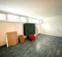 Ein Zimmer in einem Einfamilienhaus mit einem Boden in Holzoptik, Fenstern und Pappkartons.