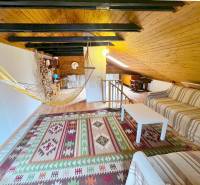 Dachboden der Hütte mit Sofa, Hängematte und Boden in Holzoptik.