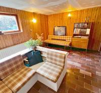 Innenraum der Hütte mit Wohnzimmer, rustikalen Möbeln und Ziegelboden.