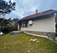 Hütte bei Modra mit einer Rasenfläche, Steintreppen und Nadelbäumen.