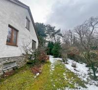 Garten bei der Hütte in Modra mit Rasen, Schnee und Gehölzen entlang des Hauses.