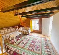 Das Dachgeschoss der Hütte mit einer Holzdecke, einem gestreiften Sofa und einem hängenden Schaukelstuhl.