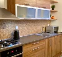 Küche mit Holzdekor und eingebauten Geräten in einer 3-Zimmer-Wohnung.