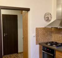 Küche in einer 3-Zimmer-Wohnung mit einem Gasherd, Mosaikfliesen und einem Boden mit Holzdekor.