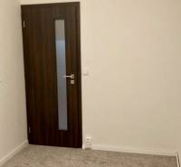 Ein Zimmer in einer 3-Zimmer-Wohnung mit Teppichboden und dunklen Türen.