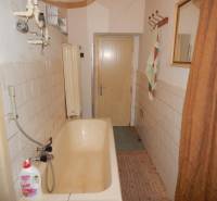 Ein Badezimmer in einem Einfamilienhaus mit einer älteren Badewanne und Fliesen an den Wänden.