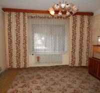 Ein Zimmer in einem Einfamilienhaus mit blumengemusterten Tapeten und einem zentralen Kronleuchter.