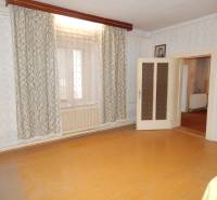 Ein Zimmer in einem Einfamilienhaus mit einem Boden in Holzoptik und Vorhängen.