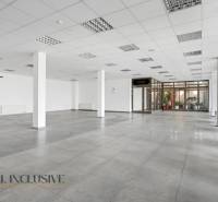 Geräumige Geschäftsräume mit Fliesen, großen Fenstern und weißen Wänden.