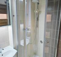 Badezimmer mit verglaster Duschkabine und hellen Fliesen in einem Studio.