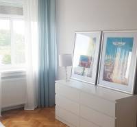 Schlafzimmer in einer Einzimmerwohnung mit Schrank, Kronleuchter und Boden in Holzoptik.