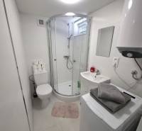 Badezimmer mit Badewanne, Waschmaschine, Boiler und Waschbecken in einer Hütte. Minimalistisches Design.