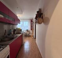 Küche in einer 2-Zimmer-Wohnung mit Holzboden und Essbereich im Hintergrund.