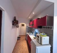 Küche mit roten Schränken und Holzboden in einer 2-Zimmer-Wohnung.