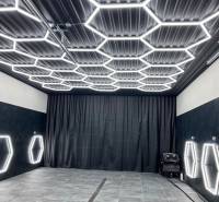 Geschäftsräume mit dunklem Dekor und sechseckiger LED-Beleuchtung an Decke und Wänden.