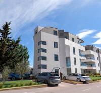 Ferienwohnung in der Stadt Pag mit modernem Gebäude und Parkplatz.