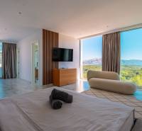 Helles Schlafzimmer in der Villa mit Blick durch große Fenster, Holzboden.
