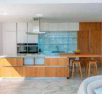 Küche in der Villa mit Holzboden, Kücheninsel und Barhockern.