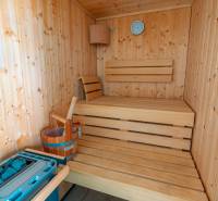Holzsauna in der Villa mit Bänken, Thermometer und Wassereimer.