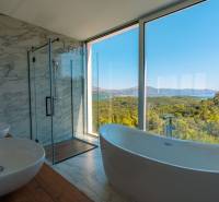 Luxuriöses Badezimmer in einer Villa mit Blick auf das Meer und die Natur, Boden mit Holzdekor.